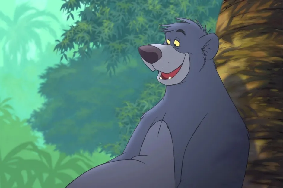 Baloo bear smiling and leaning against a tree in a lush green jungle setting, classic animated character scene.