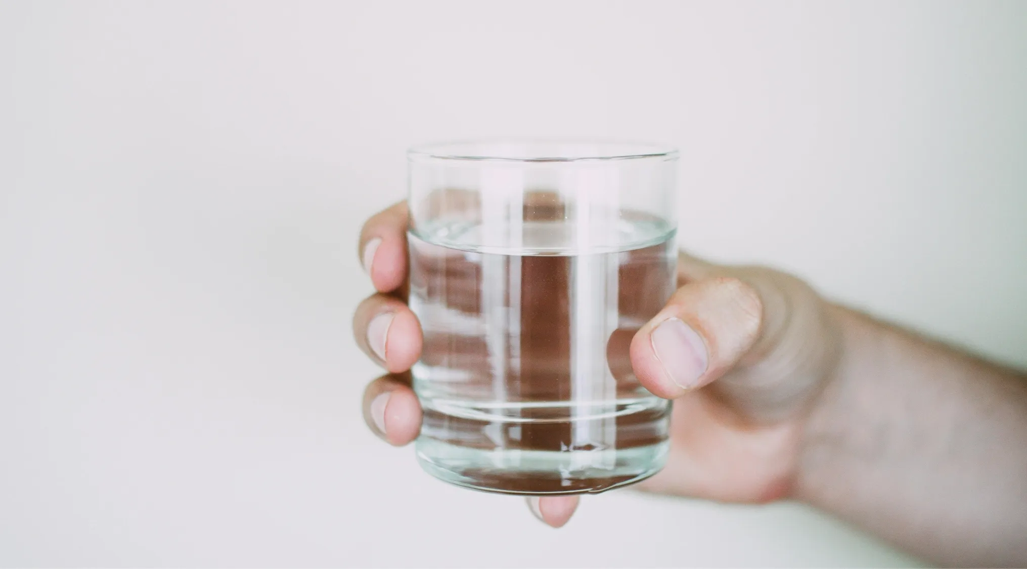 Hand holding a clear glass of water, illustrating the concept that more than 50% of the heart is water.