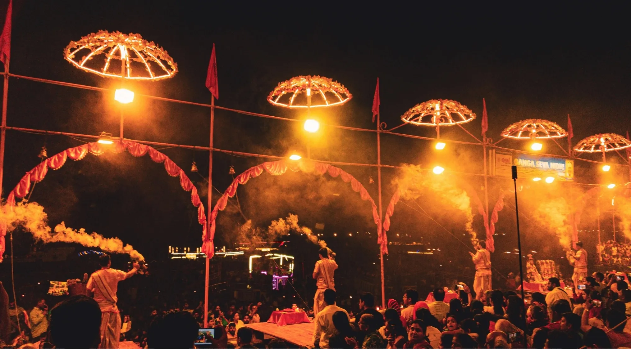 Crowd watching traditional Indian ceremony with men holding flaming fans at night, relating to India’s national animal quiz.