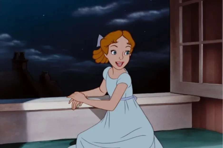 Young Wendy Darling in a blue dress looking out at the night sky from an open window in an animated scene.