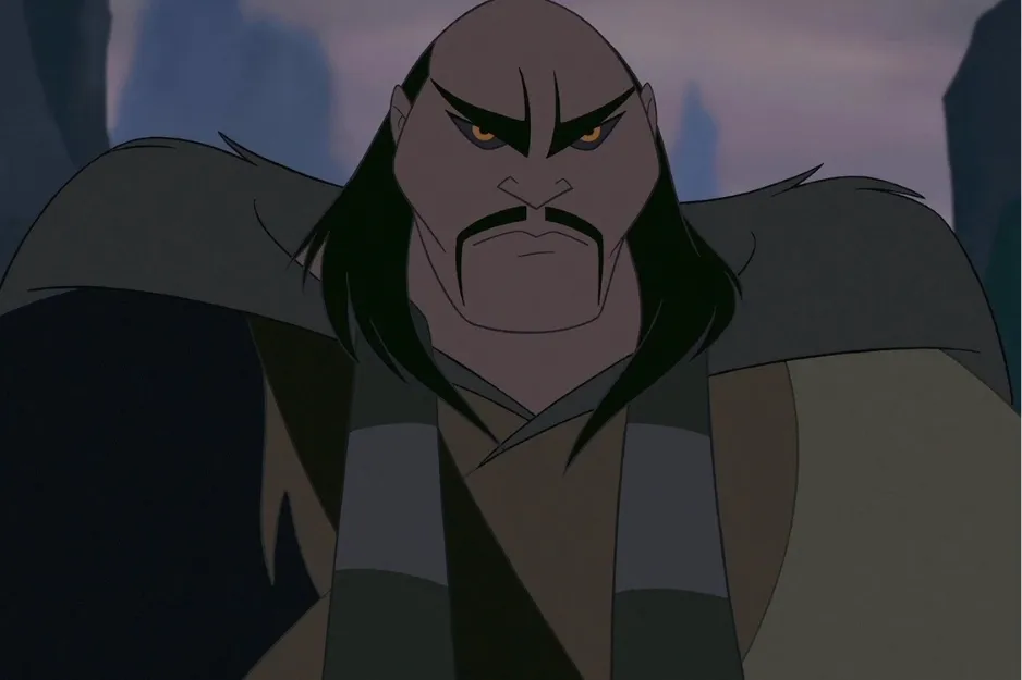 Shan Yu character from animated movie with stern expression wearing dark gray and brown clothing in a dim setting.