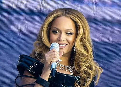 Beyoncé performing at the 2019 Super Bowl halftime show, holding a microphone and smiling on stage.