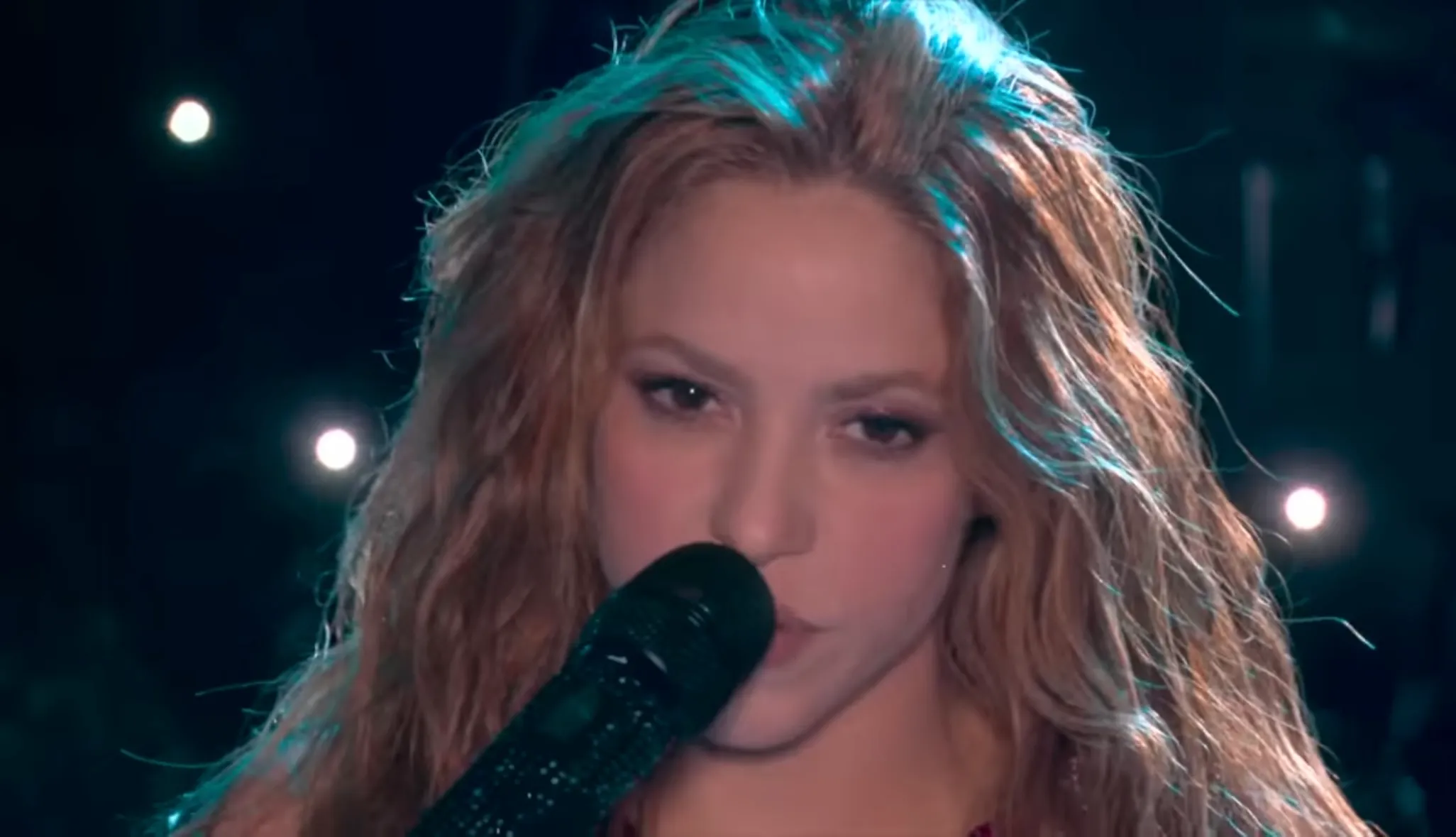 Shakira singing into a microphone during the 2019 Super Bowl halftime show performance.
