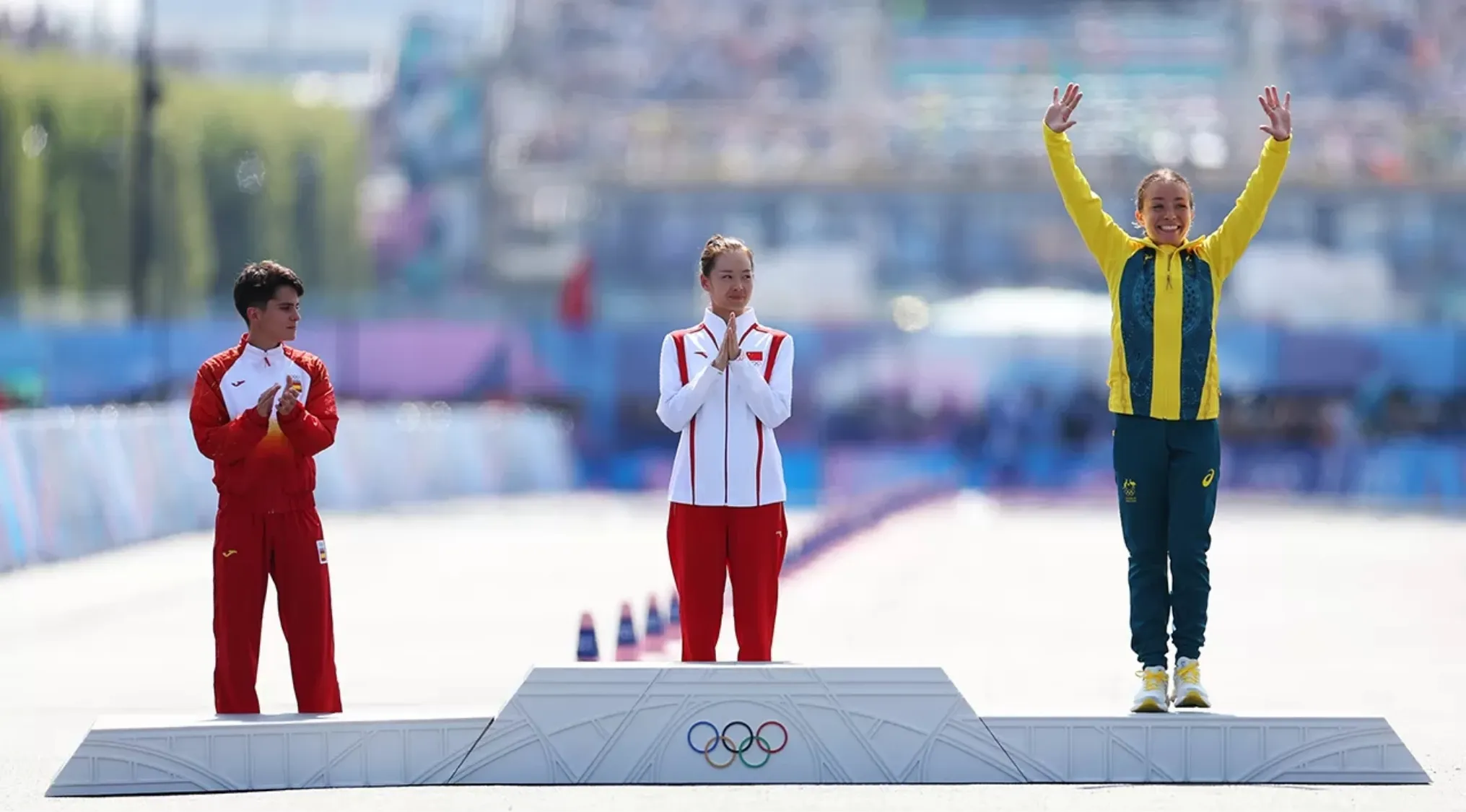Athletes standing on an Olympic podium with gold, silver, and bronze medals awarded at a historic Olympic Games ceremony.