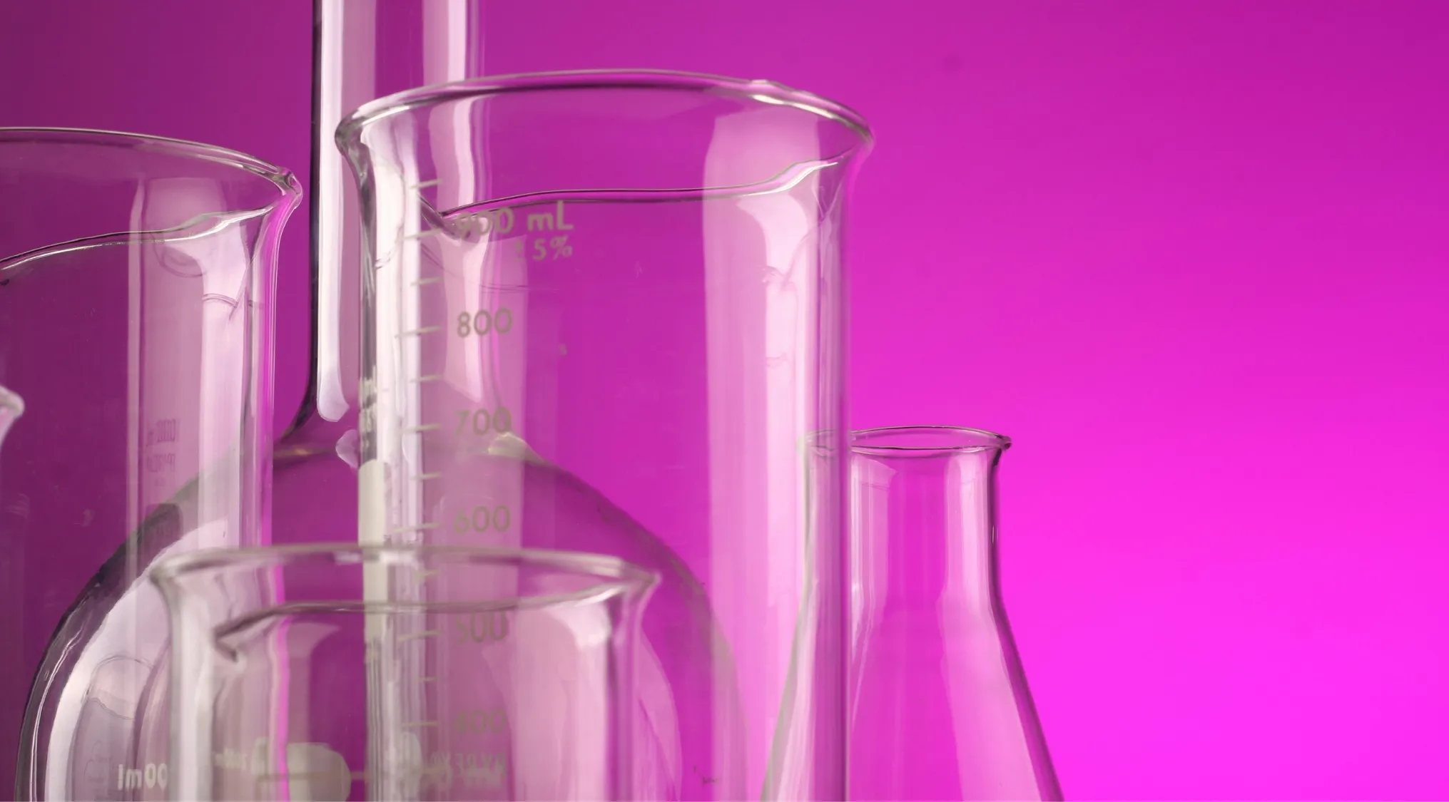 Clear glass chemical beakers and flasks against a purple background for difficult general knowledge quiz concept.
