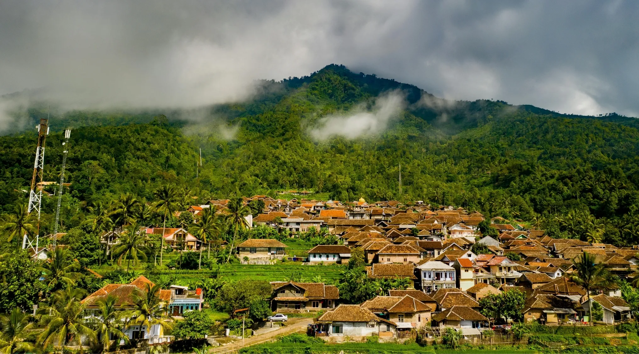 Village with traditional houses at the foot of a lush mountain, illustrating European power controlling Indonesia before World War II