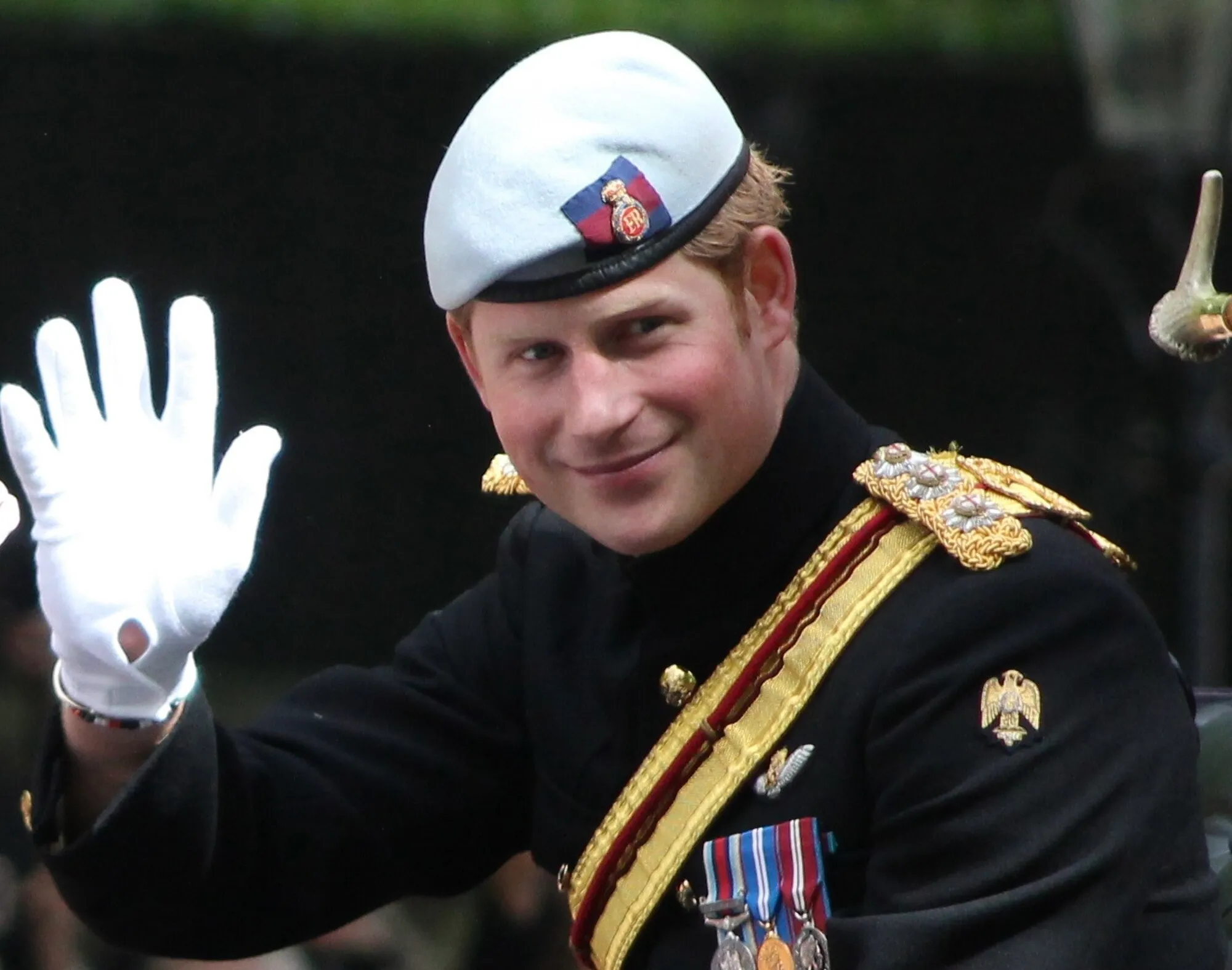 Prince Harry in military uniform waving, representing his role in establishing the Invictus Games for wounded veterans.