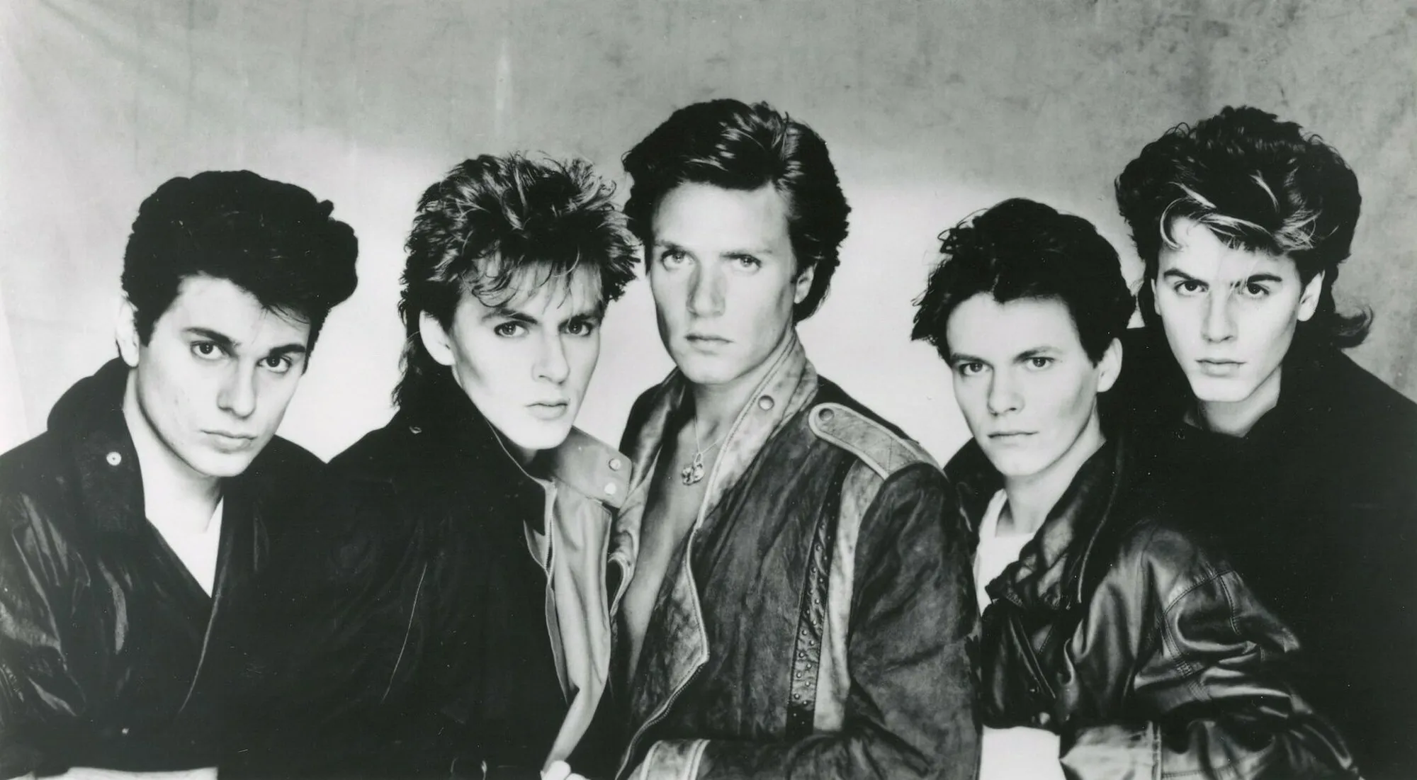 Black and white photo of a 1990s band known for the song All That She Wants, posing in leather jackets.