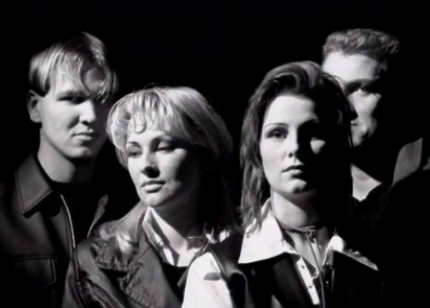 Black and white photo of the music band Ace of Base from the 1990s with four members posing against a dark background.