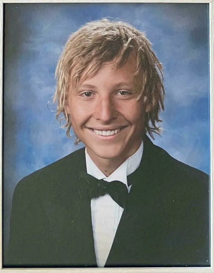 Young man with uneven, messy hair in a formal suit and bow tie, illustrating a tragic hair accident from hairstylist mishaps.
