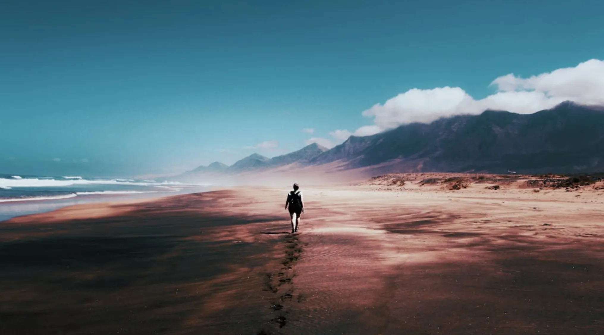 Person walking on a vast beach leaving footprints, illustrating basic math skills in distance measurement in meters.
