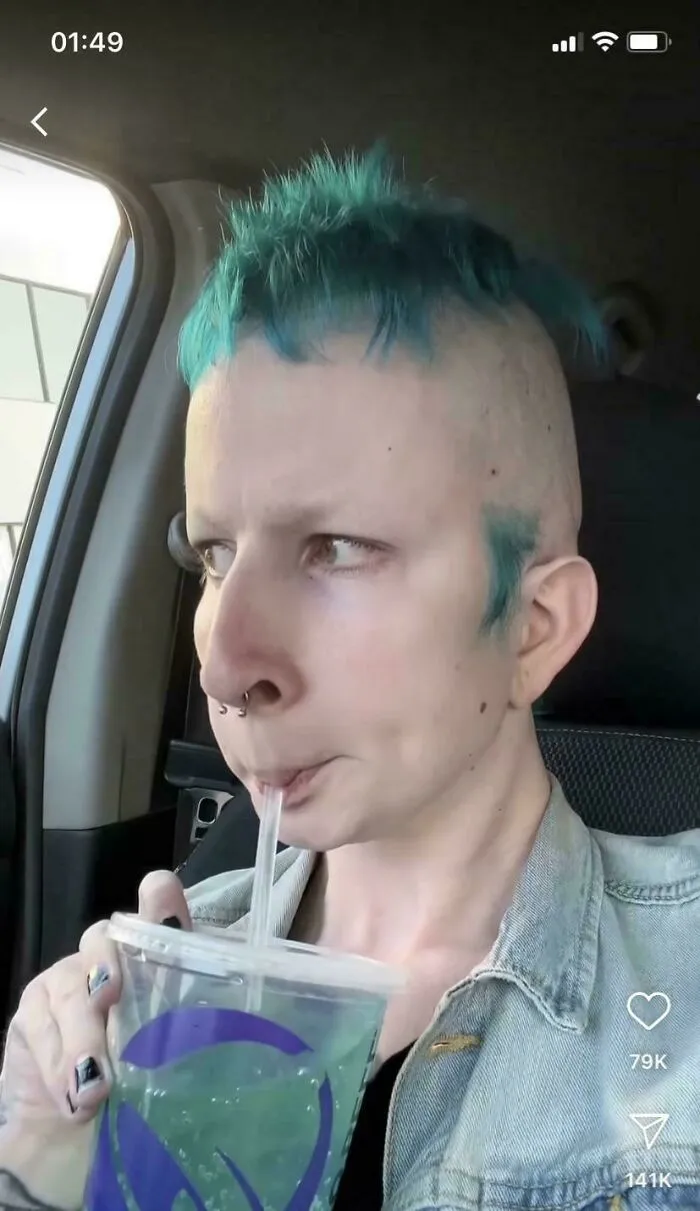 Person with uneven, tragic hair accident dye and haircut sipping a drink in a car, showing a hairstylist fail.