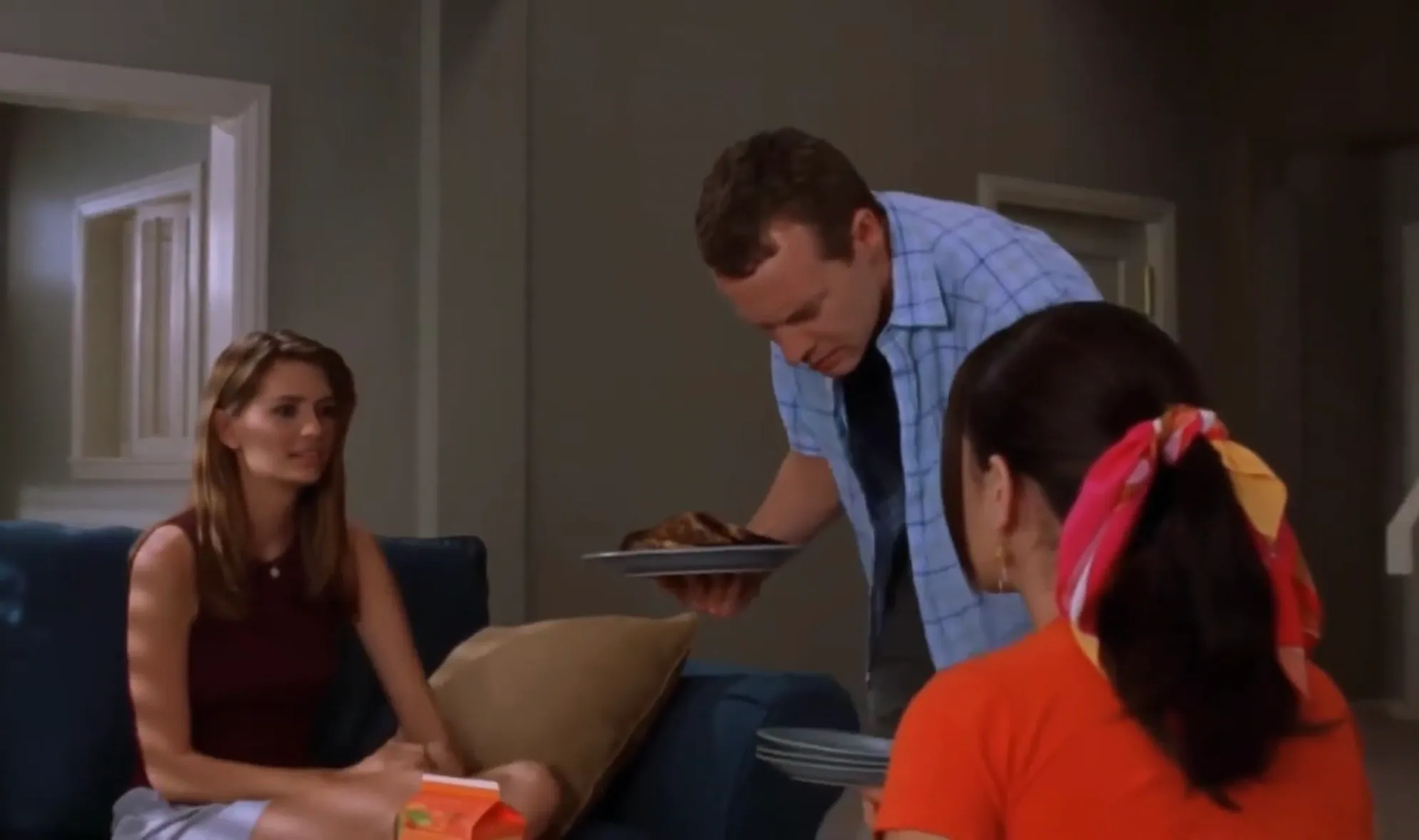 Teen drama scene with Brandon Walsh serving food to friends Kelly Taylor and others in a 1990s high school setting.