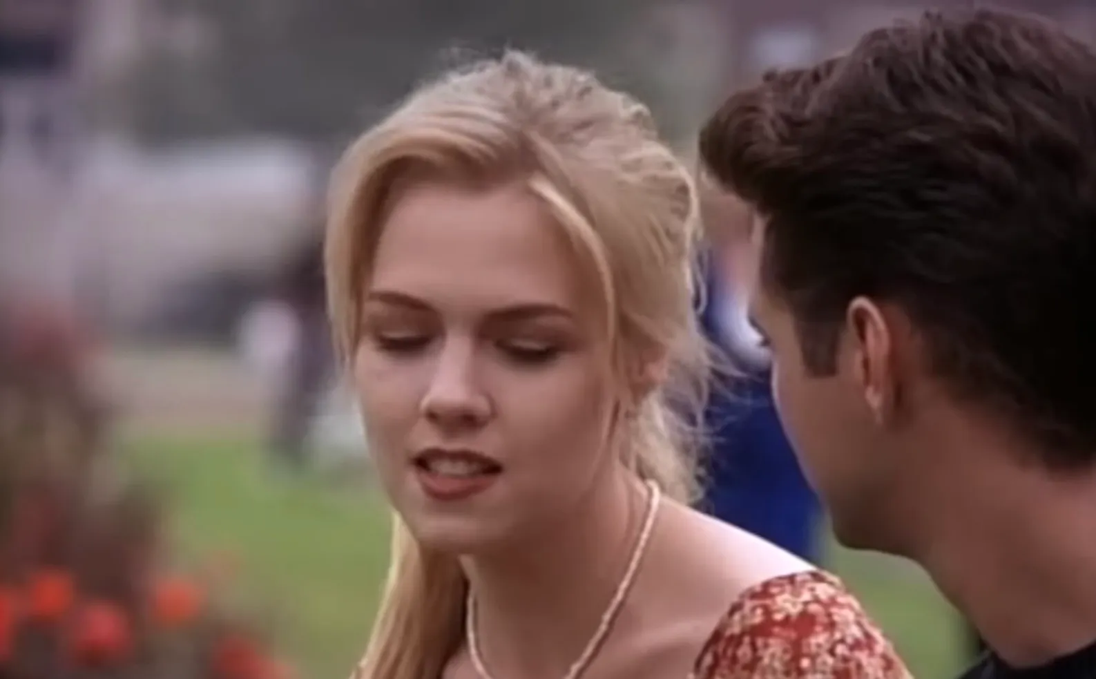 Teen drama scene with Brandon Walsh and Kelly Taylor talking outdoors, reflecting 1990s Beverly Hills 90210 high school life.