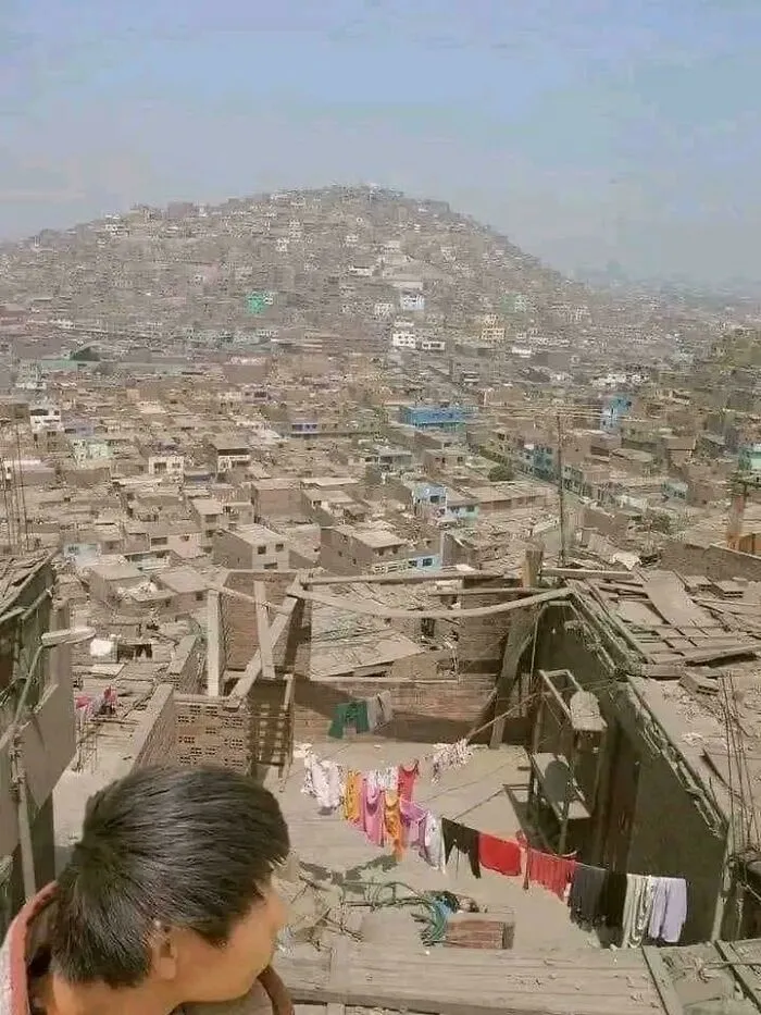 View of a sprawling dystopian urban hell with densely packed housing and makeshift rooftops in modern life setting.