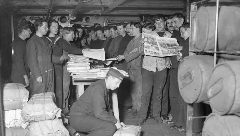 Group of World War I soldiers in uniform reading newspapers on a ship, related to the general knowledge quiz on the war's beginning year.