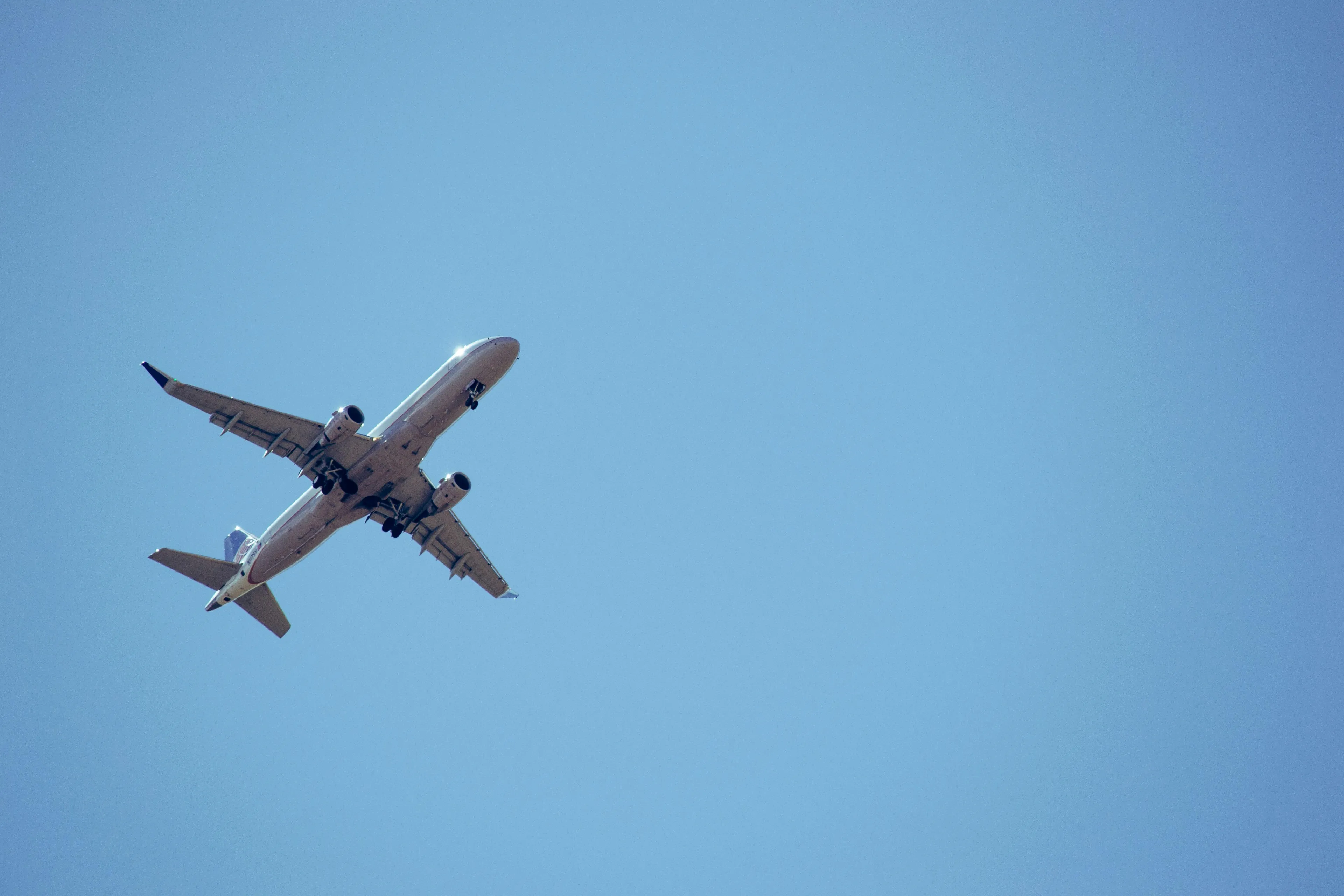 Passenger airplane flying in blue sky representing psychological defense mechanisms during flight delay.