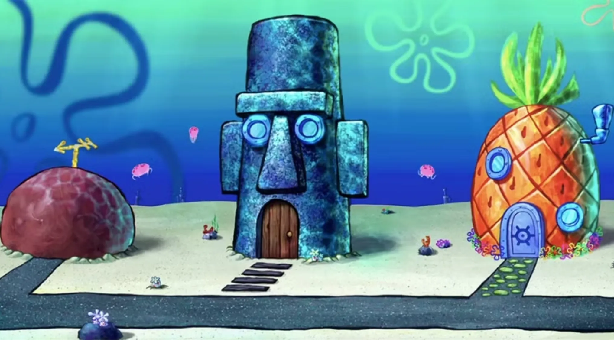 Underwater scene showing a pineapple house, Easter Island head house, and rock house in a cartoon sea setting.