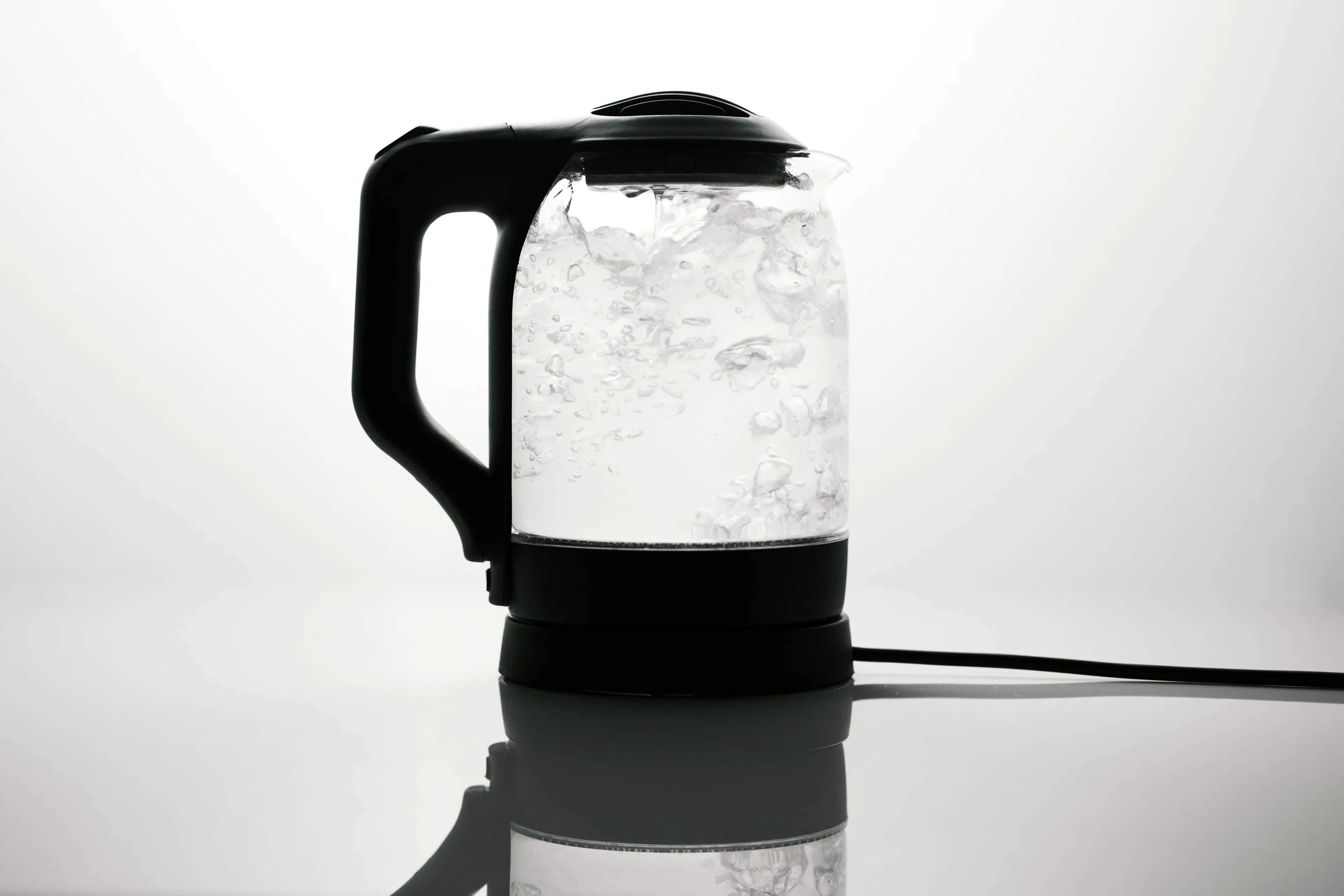 Electric kettle boiling water with bubbles visible, related to freezing point of water in degrees Celsius concept.
