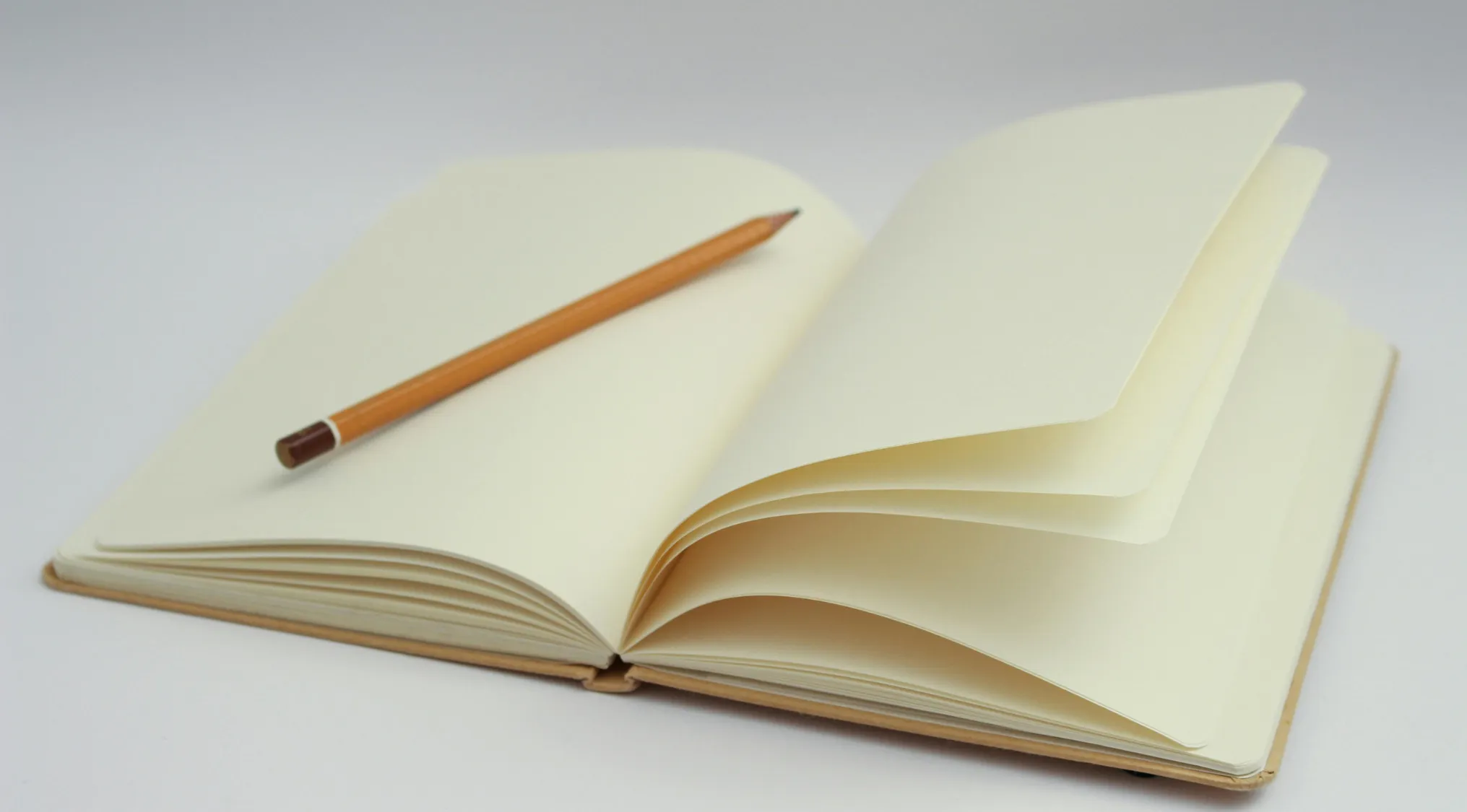 Open blank notebook with pencil resting on pages, symbolizing advanced placement school quiz in English language.