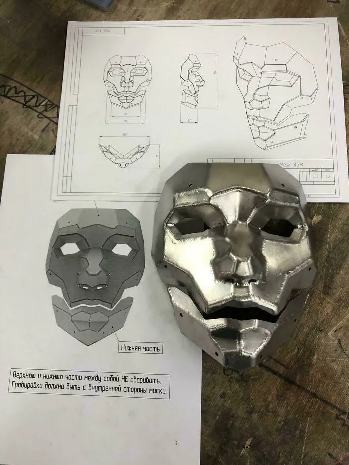 Metalworkers crafted a remarkable geometric metal face mask shown alongside detailed design blueprints.