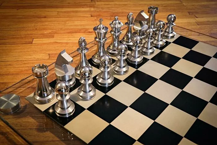 Polished metal chess pieces on a wooden board showcasing remarkable craftsmanship by metalworkers.