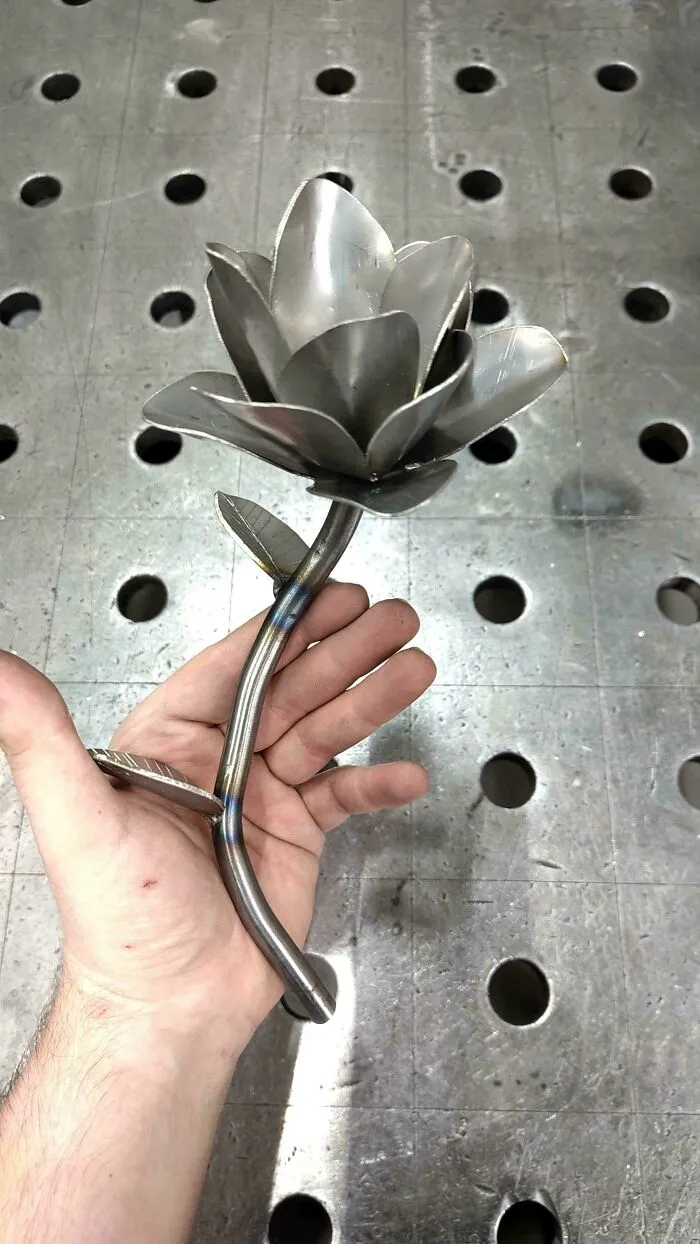 Hand holding a metal flower sculpture showcasing metalworkers' skill in defying physics and logic with remarkable craft.