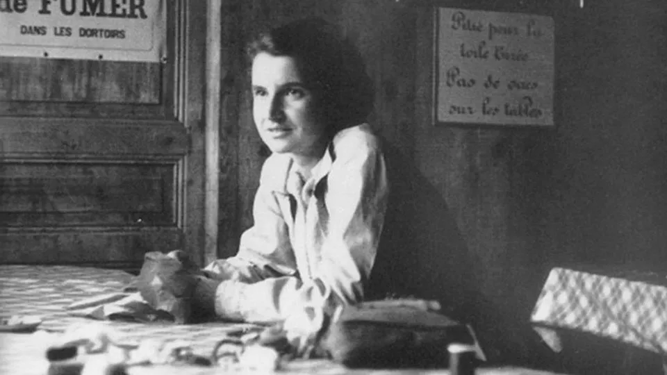 Black and white photo of a woman sitting at a table, related to general knowledge quiz about Nobel Prize winners.