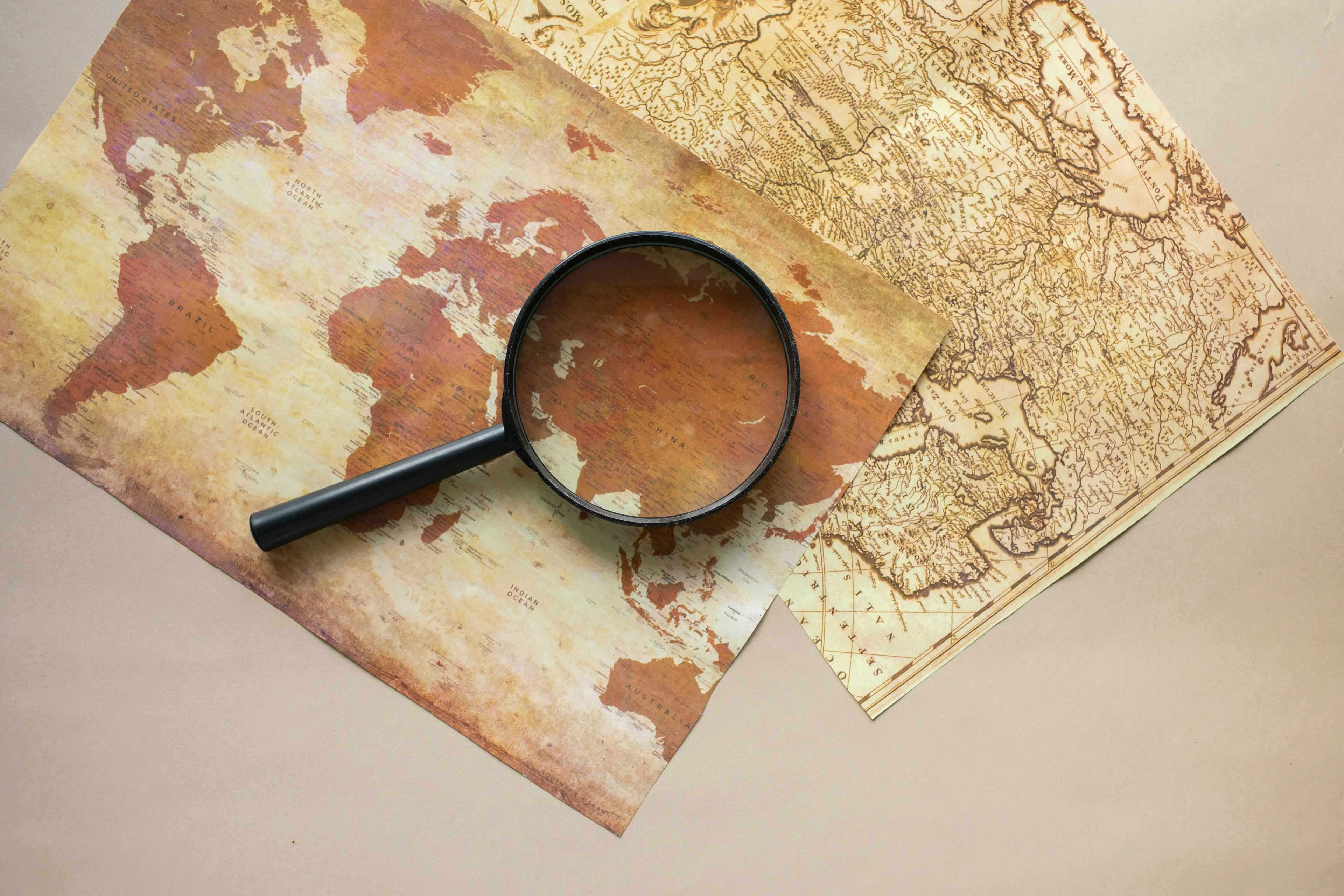 Magnifying glass over vintage world map, representing general knowledge quiz about European and African continents strait.
