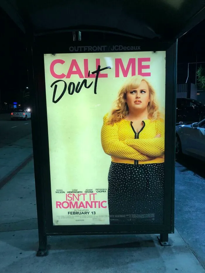 Bus stop sign with graffiti altering movie poster text, showcasing a sign that went wrong and turned into comedic gold.