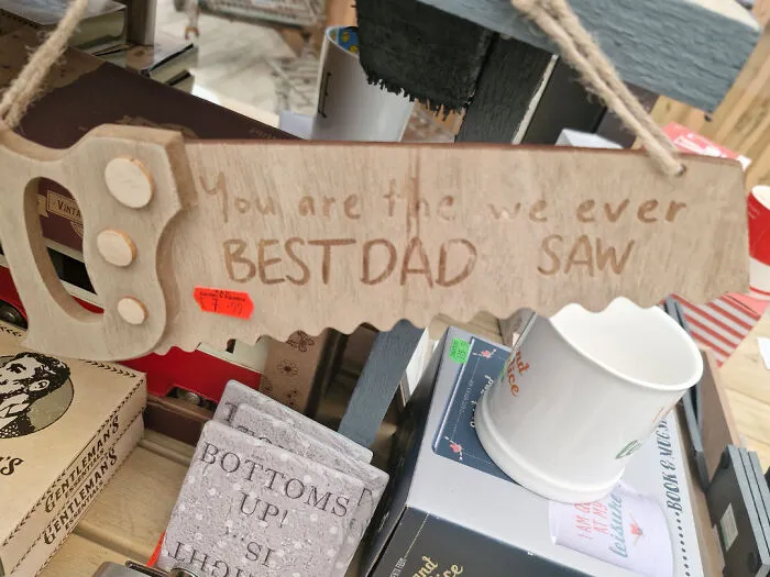 Wooden saw-shaped sign with misspelled message about best dad, a funny example of signs that went wrong.