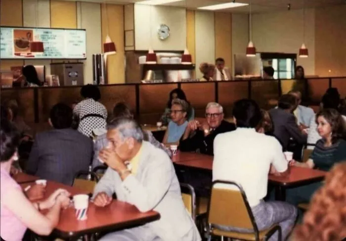 A bustling retro diner scene with customers enjoying meals, reminding you how old some places look.