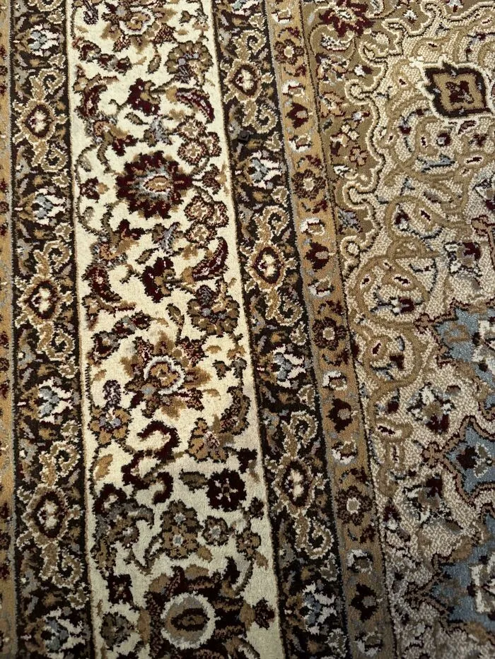 Spider camouflaged on a patterned carpet blending perfectly with the intricate designs in a tricky hidden object scene.