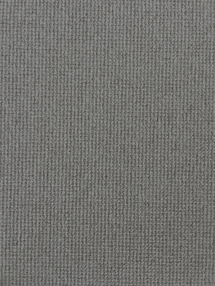 Gray textured fabric close-up with a perfectly camouflaged object blending into the pattern, hard to find at first glance.