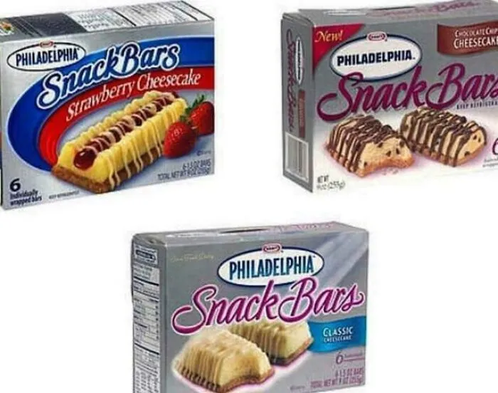 Three boxes of Philadelphia Snack Bars in strawberry cheesecake, chocolate chip cheesecake, and classic cheesecake flavors, 90s nostalgic treats.