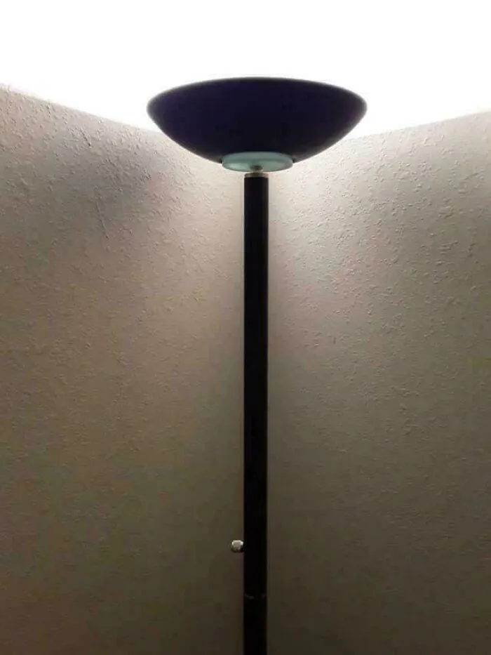 Tall black floor lamp casting light on textured white walls, evoking nostalgic memories from the 90s era.
