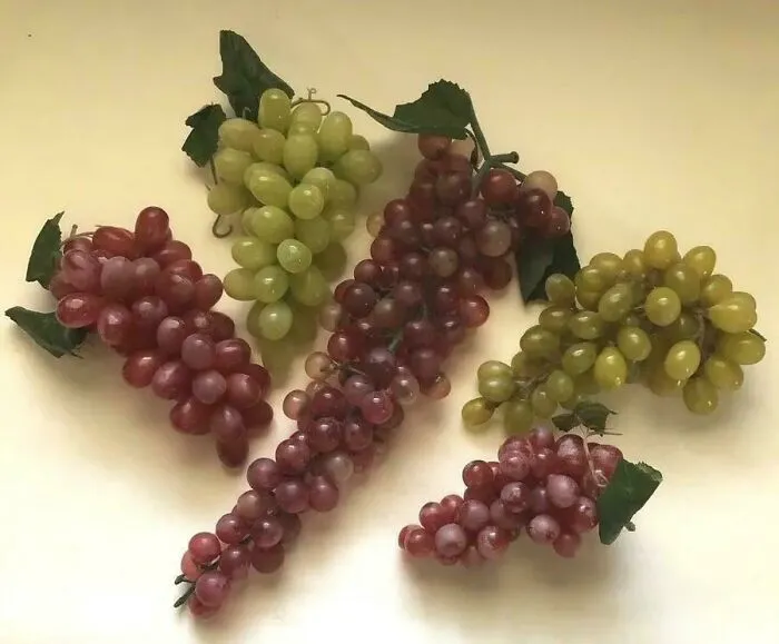 Clusters of realistic vintage grapes toys from the ’90s nostalgia collection on a neutral background.