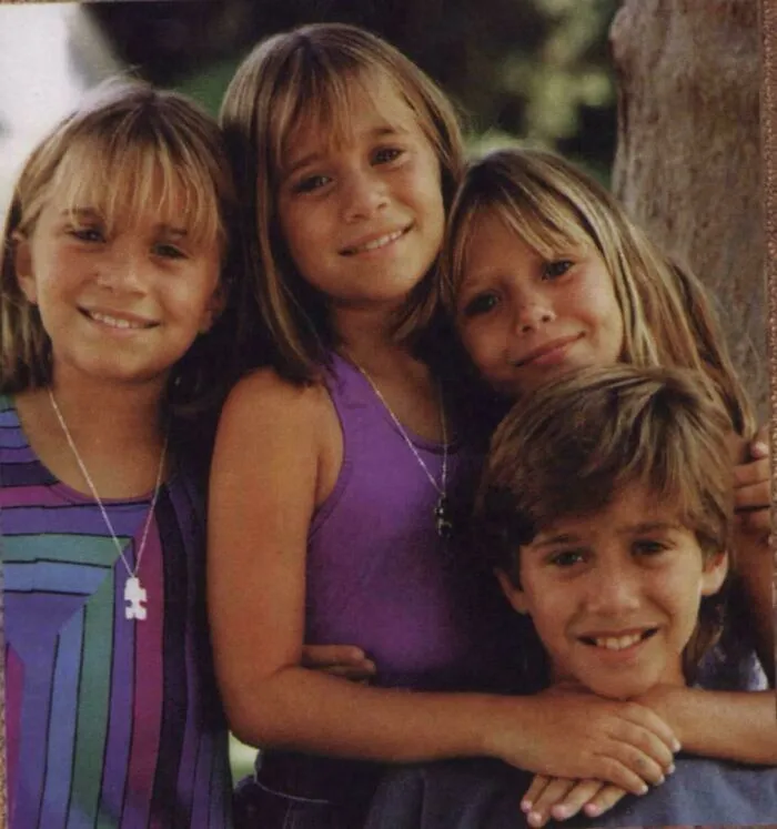 Group of smiling kids from the ’90s wearing colorful clothing, capturing nostalgic memories of childhood and friendship outdoors.