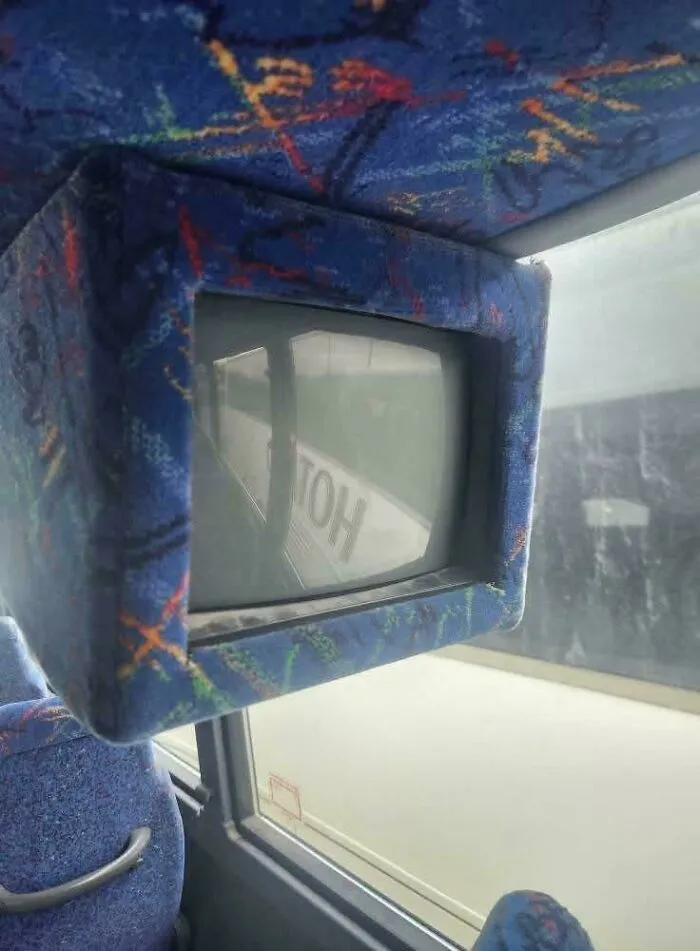 Old bus interior with nostalgic CRT TV screen framed by patterned blue fabric, evoking 90s memories and vintage travel experience.