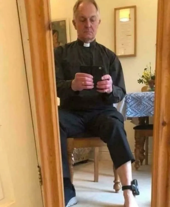 Priest taking a selfie wearing a leg monitor in a confusing and weird cursed image.