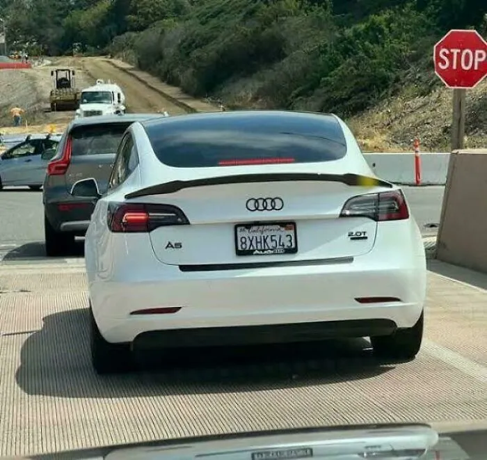 White Audi A5 with a Tesla rear design caught in traffic, one of the weird and confusing cursed images you won’t unsee.