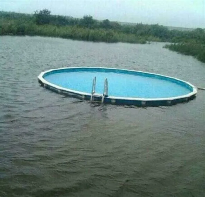 Above-ground swimming pool floating in a flooded area, creating a weird, confusing, and cursed visual effect.