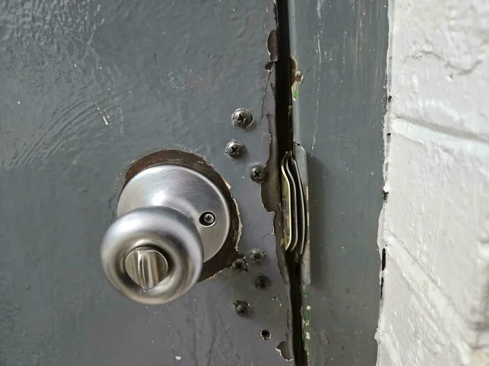 Door latch gap fixed with stacked coins as a technically works but dumb solution to door problems.