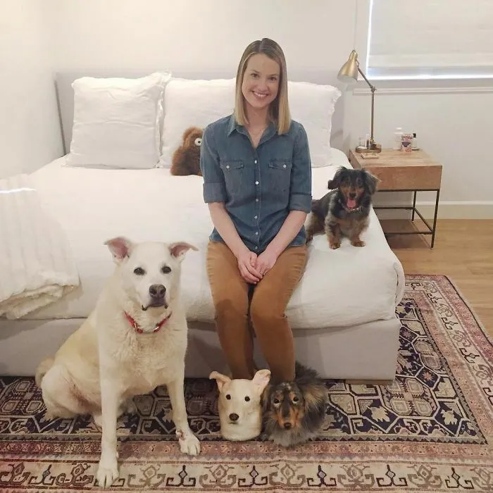 Woman sitting on bed with dogs next to a realistic dog mask