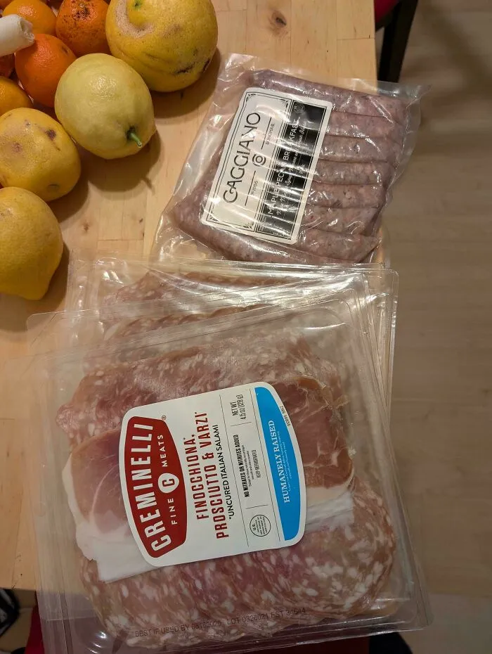 Packaged meats and fresh lemons on a wooden surface, highlighting a fortunate dumpster diving find.