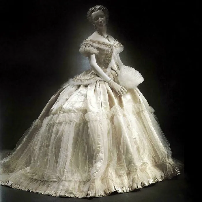 Woman mannequin dressed in a historical garment with an elaborate silk gown and lace, showcasing vintage fashion style.