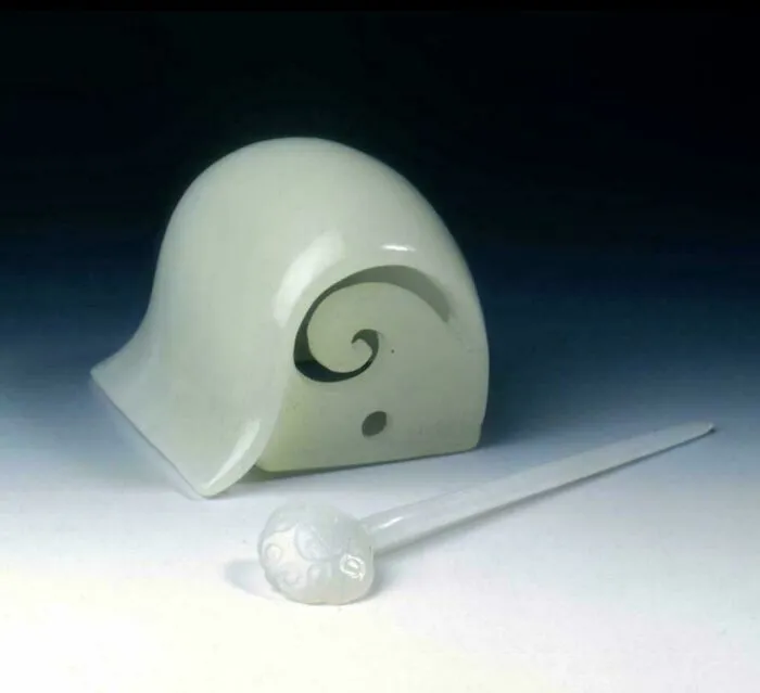 Ancient white jade artefact with intricate spiral design and matching carved stick, a fascinating artefact from history.