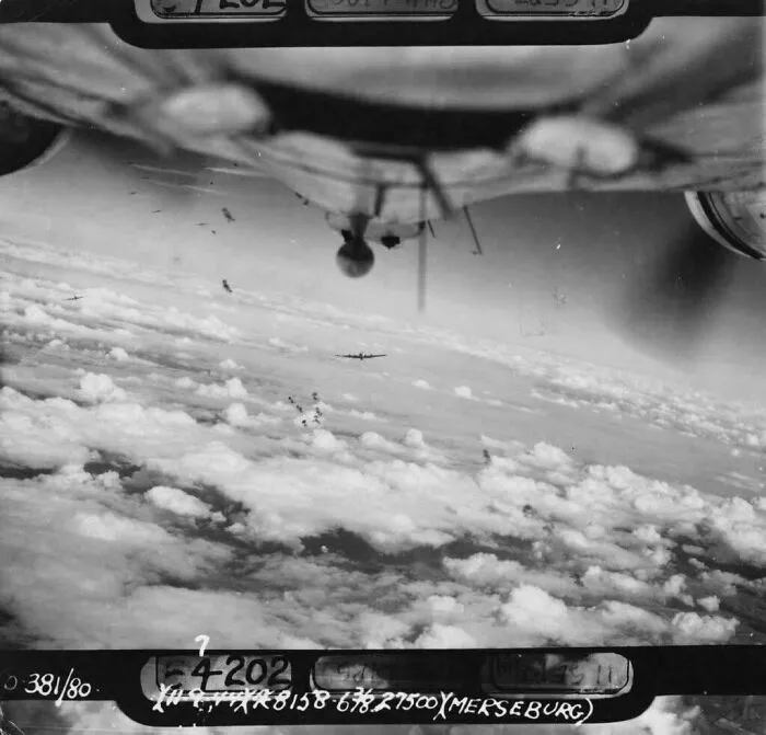 Black and white historical photo of World War II bomber planes flying above the clouds during a mission.