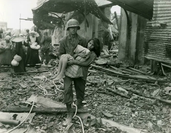 Un soldado estadounidense transporta a una niña filipina herida entre los escombros de Manila, 23 de febrero de 1945.