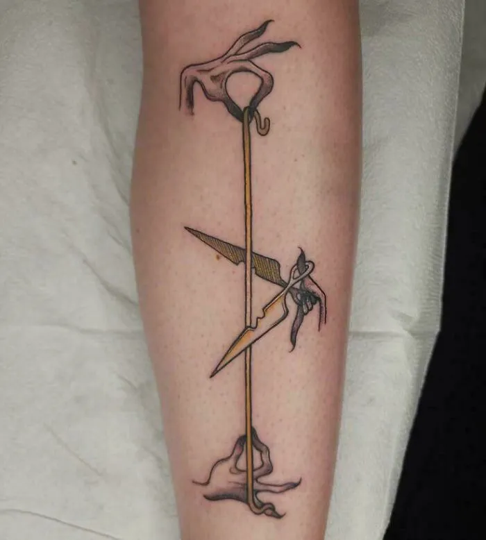 A stunning tattoo featuring abstract hands, a golden line, and sharp dagger-like forms on a person's leg.